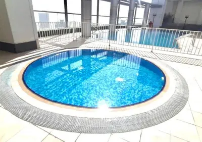 a large swimming pool with blue water in a building at RH- Chic & Sleek Studio apartment, near Burj Khalifa in Dubai