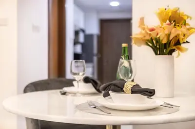 a white table with a plate and a vase of flowers at The Smart Concierge - Waves By KASCO in Dubai