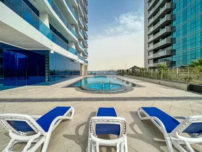 a group of chairs and a swimming pool on a building at The Smart Concierge - Waves By KASCO in Dubai