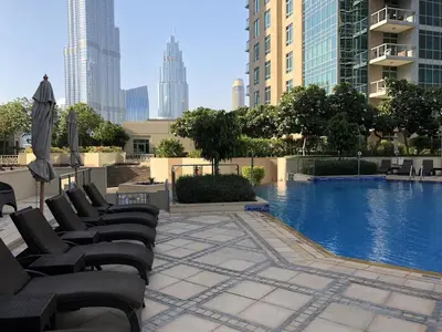 a pool with chairs and an umbrella in a city at Elite Royal Apartment - Full Burj Khalifa & Fountain View - Grace in Dubai