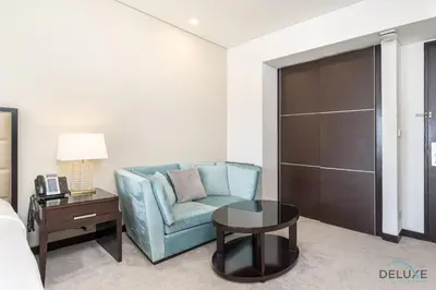 a living room with a blue couch and a table at Marina Canal Views Next to Mall & Marina Promenade Studio Unit, The Address Residences, Dubai Marina by Deluxe Holiday Homes in Dubai