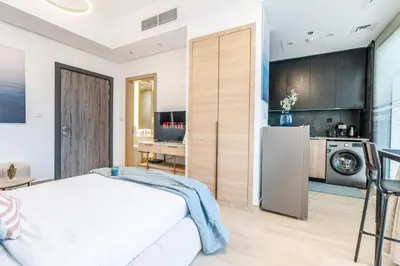 a bedroom with a white bed and a kitchen at GuestReady - Zen in the heart of JVC in Dubai