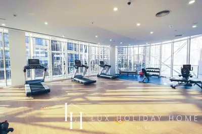 a gym with treadmills and ellipticals in a room with windows at LUX The Pad Executive Suite Canal View 4 in Dubai