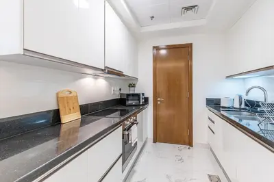 a kitchen with white counters and a wooden door at Hashtag Holiday Home - 1BDR Apartment with Canal View in Business Bay in Dubai