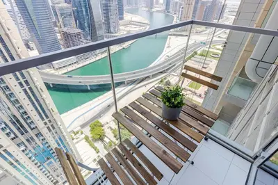 a balcony with two benches and a river and a bridge at Hashtag Holiday Home - 1BDR Apartment with Canal View in Business Bay in Dubai