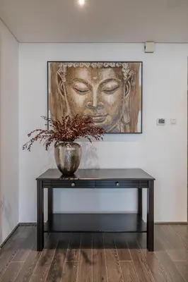 a vase on a table with a painting on a wall at Hashtag Holiday Home - Excellent 1BDR with City View in Media city in Dubai
