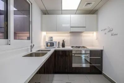 a white kitchen with a sink and a microwave at Hashtag Holiday Home - Excellent 1BDR with City View in Media city in Dubai