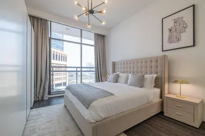 a bedroom with a large bed and a large window at Hashtag Holiday Home - Excellent 1BDR with City View in Media city in Dubai