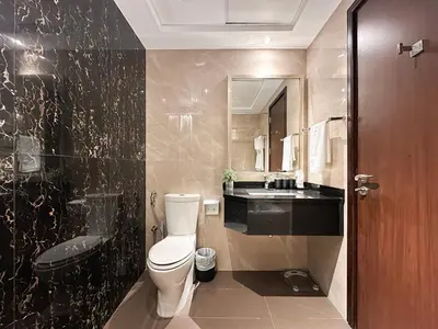 a bathroom with a toilet and a sink and a mirror at Trophy - Downtown Scape Views Suite in Dubai