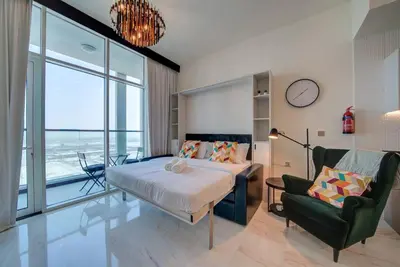a bedroom with a bed and a chair and a clock at Lovely studio in Business Bay in Dubai