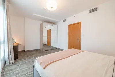 a white bedroom with a bed and a mirror at 1BDR Apartment in Dubai Marina with Marina Views in Dubai