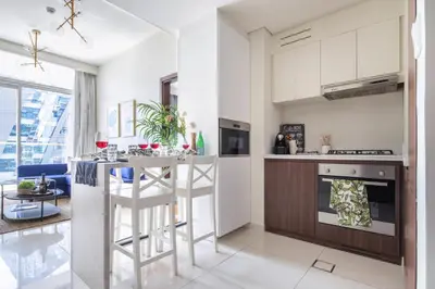 a kitchen with white cabinets and a bar with stools at Frank Porter - Vera Residence in Dubai