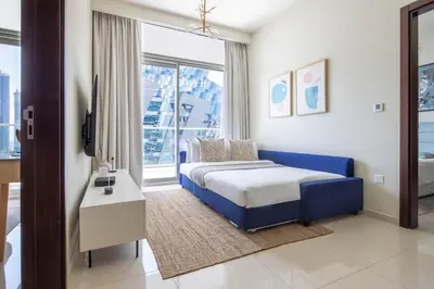 a bedroom with a blue bed and a large window at Frank Porter - Vera Residence in Dubai