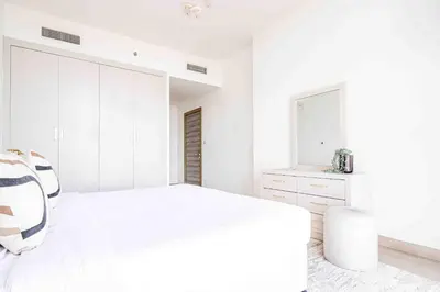 a white bedroom with a large bed and a mirror at Frank Porter - Bloom Tower A in Dubai