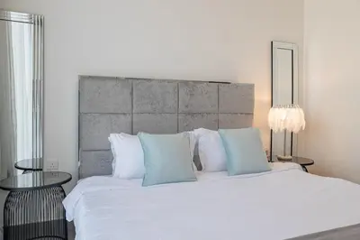 a bedroom with a large bed with white sheets and blue pillows at Spacious 2BDR in Creek Harbor with City View in Dubai