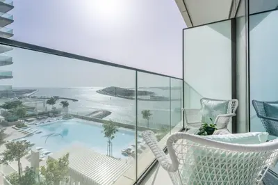 a balcony with a white chair and a swimming pool at GuestReady - Sea View Escape In Marina in Dubai