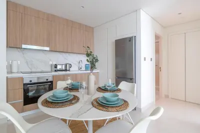 a white kitchen with a white table and chairs at GuestReady - Sea View Escape In Marina in Dubai