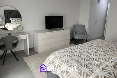 a bedroom with a bed and a tv and a chair at Birchfort - Newly renovated unique 1 bedroom apartment in Dubai