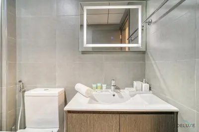 a bathroom with a sink and a toilet and a mirror at Refined 1BR at Bella Rose Barsha South by Deluxe Holiday Homes in Dubai
