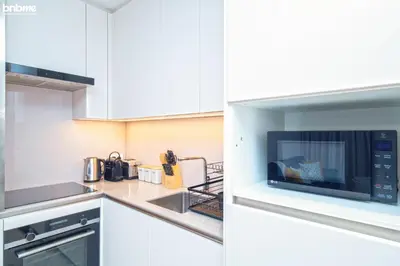 a kitchen with white cabinets and a microwave at bnbme - Luxury 1BR Marina View Apt w Balcony Pool Gym Access Near JBR Beach & Walk in Dubai
