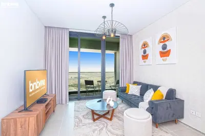 a living room with a blue couch and a tv at bnbme - Luxury 1BR Marina View Apt w Balcony Pool Gym Access Near JBR Beach & Walk in Dubai