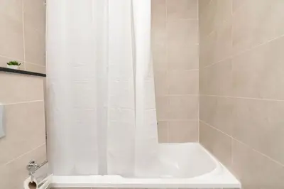 a shower with a white shower curtain in a bathroom at Gala Guests - Carson Studio Collection in Dubai