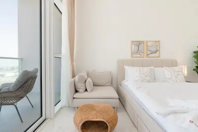 a bedroom with a bed and a chair and a window at Gala Guests - Carson Studio Collection in Dubai