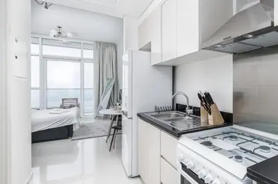 a white kitchen with a sink and a stove at Gala Guests - Carson Studio Collection in Dubai