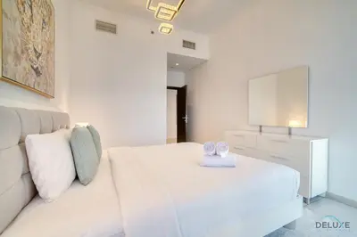a white bedroom with a bed and a tv at Sea Views from Living to Bedroom Perfect for Staycation, Dubai Marina by Deluxe Holiday Homes in Dubai