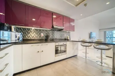 a kitchen with purple cabinets and two bar stools at Sea Views from Living to Bedroom Perfect for Staycation, Dubai Marina by Deluxe Holiday Homes in Dubai
