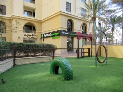 a playground with a tire on the grass in front of a building at La Buena Vida Holiday Homes - Beach front very spacious, luxe and modern 3 bedroom with full kitchen in JBR , 3 min to the JBR beach Dubai Marina and Tram Station in Dubai