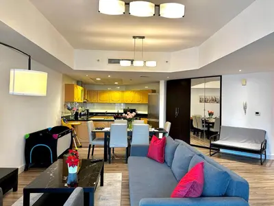 a living room with a blue couch and a dining room at La Buena Vida Holiday Homes - Exquisite Spacious Luxe 1BR Apt , Full Marina View, Kitchen, 5 Min to Beach, JBR and Marina in Dubai