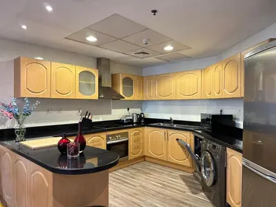 a kitchen with wooden cabinets and a black counter top at La Buena Vida Holiday Homes - Exquisite Spacious Luxe 1BR Apt , Full Marina View, Kitchen, 5 Min to Beach, JBR and Marina in Dubai