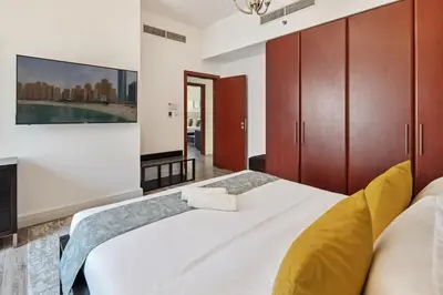 a bedroom with a large white bed with wooden cabinets at La Buena Vida Holiday Homes - Modern, Luxe & Spacious 4-Bed, Full Kitchen, near to Beach, Tram & Marina in Dubai