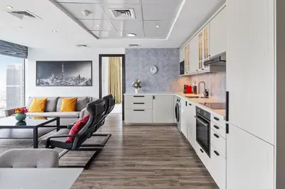 a kitchen with white cabinets and a table and chairs at Modern & Spacious 2-Bed Condo with Panoramic Lake Views, Dual Balconies, Steps from Dubai JLT Metro By 