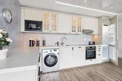 a kitchen with white cabinets and a washer and dryer at Modern & Spacious 2-Bed Condo with Panoramic Lake Views, Dual Balconies, Steps from Dubai JLT Metro By 
