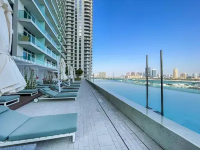 a hotel swimming pool with chairs and a building at Emaar Beach Front 2BR with Sea & Marina Skyline Views in Dubai