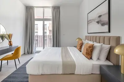 a bedroom with a bed and a desk and a window at Frank Porter - Belgravia 3 in Dubai