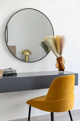 a yellow chair and a mirror and a vase with a feather at Frank Porter - Belgravia 3 in Dubai