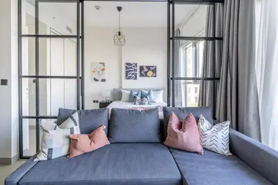 a living room with a blue couch with pillows at GuestReady - Breath of Fresh Air in Dubai Hills in Dubai
