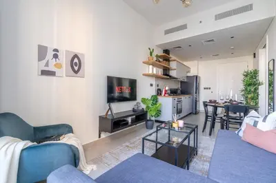 a living room with a blue couch and a tv at GuestReady - Breath of Fresh Air in Dubai Hills in Dubai