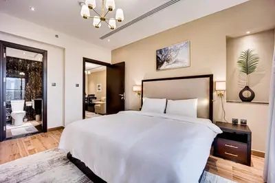 a bedroom with a large white bed and a bathroom at Amazing Burj Khalifa view from Brand new apartment in Dubai