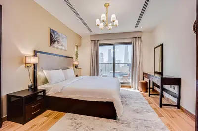 a bedroom with a bed and a desk and a window at Amazing Burj Khalifa view from Brand new apartment in Dubai