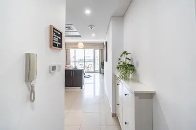 a hallway with white walls and a kitchen with a refrigerator at Cute 1BR - Dubai Marina Views - Walk 9min to Beach in Dubai