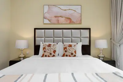 a bedroom with a large white bed with two lamps at Maison Privee - Elite Apt Connected to Dubai Mall & Burj Khalifa in Dubai