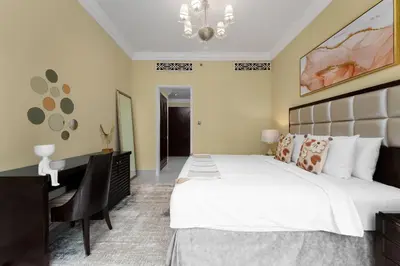 a bedroom with a large bed and a desk at Maison Privee - Elite Apt Connected to Dubai Mall & Burj Khalifa in Dubai