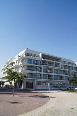 a large white building with a lot of windows at ModernLux - Lovely Studio Apartment in JVT next to Park in Dubai