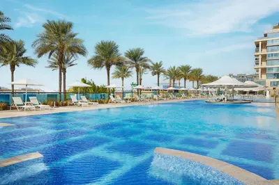 a large swimming pool with palm trees and umbrellas at Marriott Resort Palm Jumeirah, Dubai in Dubai