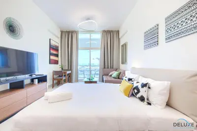 a white bedroom with a large bed and a living room at Perfect Studio Getaway Next to the Iconic Creek Harbour, Azizi Aliyah, Al Jaddaf, by Deluxe Holiday Homes in Dubai