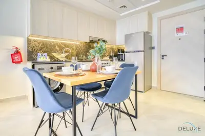 a kitchen with a wooden table and blue chairs at Homely 1BR at Binghatti Avenue Al Jaddaf by Deluxe Holiday Homes in Dubai